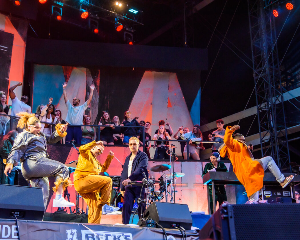 Ein Zuschauermagnet und mächtig viel los on stage: Peter Fox und Crew etablieren fast schon einen eignen Club auf dem Festival. – Viele Menschen auf der Bühne.