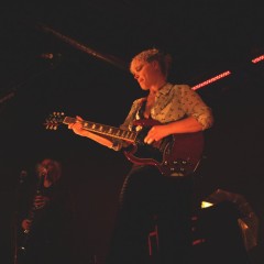 Wallis schrammelt auf der E-Gitarre. Im Hintergrund an der Klarinette: Aidan.